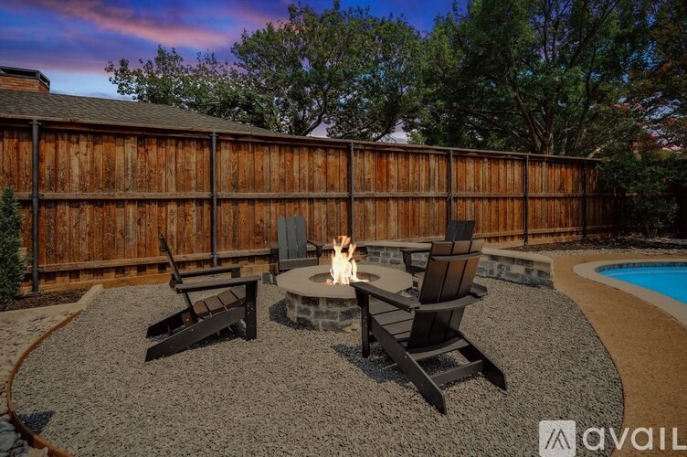 A backyard with a fire pit and chairs.
