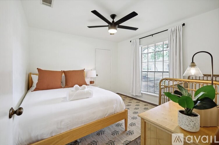 A bedroom with a bed, a table with a lamp, and a ceiling fan.
