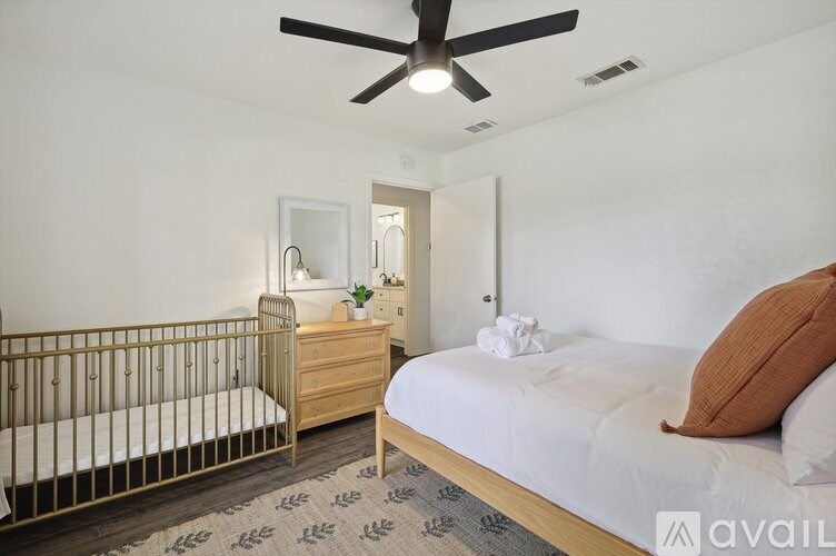 A bedroom with a bed, dresser, and crib.