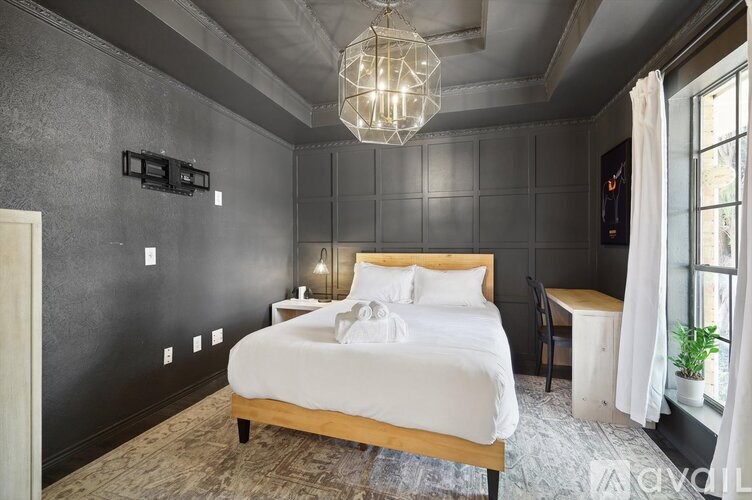 A bedroom with a large bed and a chandelier hanging from the ceiling.