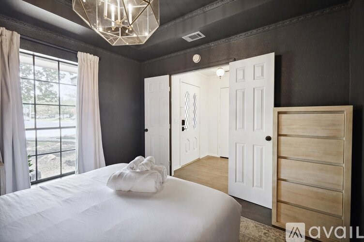 A bedroom with a large bed and a window with curtains.