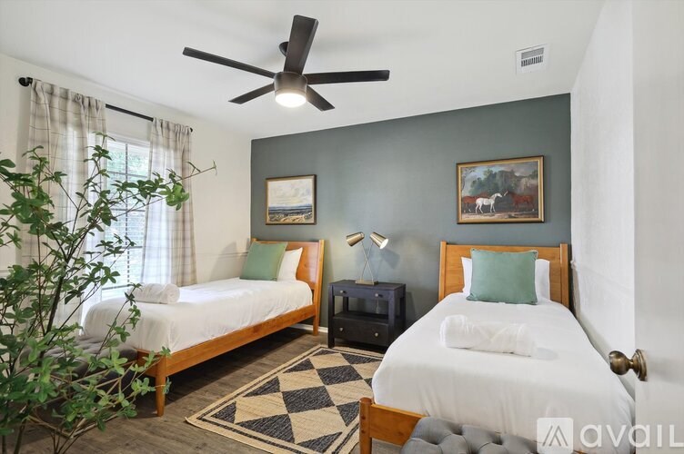 A bedroom with two beds, a ceiling fan, and a rug.