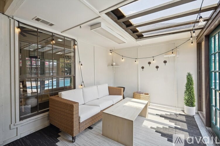 A sunny day in a room with a white sofa and a glass wall.