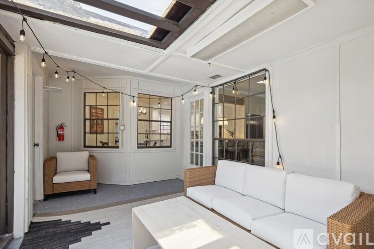 A white couch is placed in a room with a glass wall and a fire extinguisher is visible.