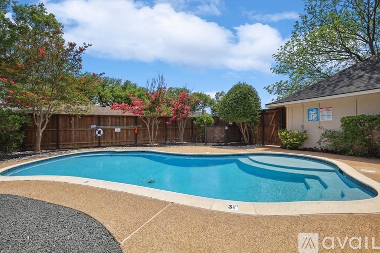 A pool surrounded by a gravel area and a wooden fence.
