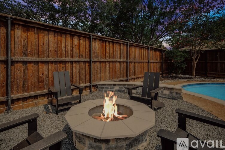 A backyard with a fire pit and chairs.