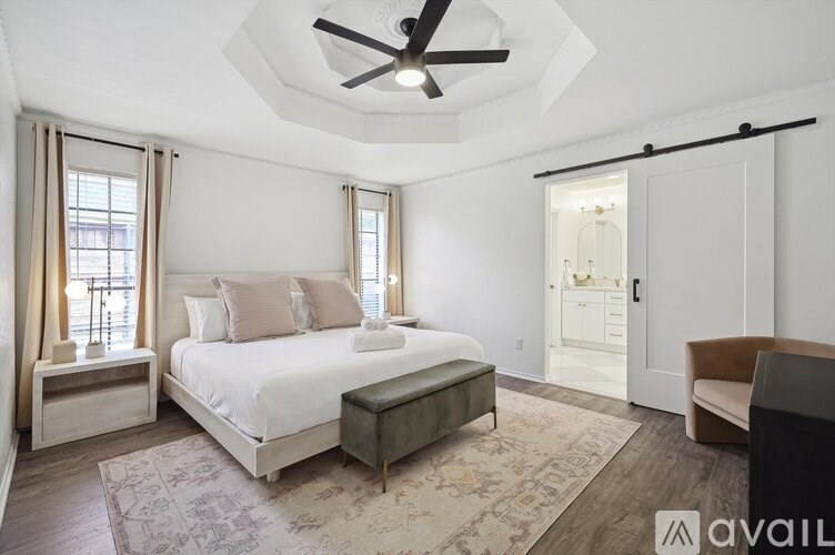 A bedroom with a bed, a bench, a ceiling fan, and a rug.
