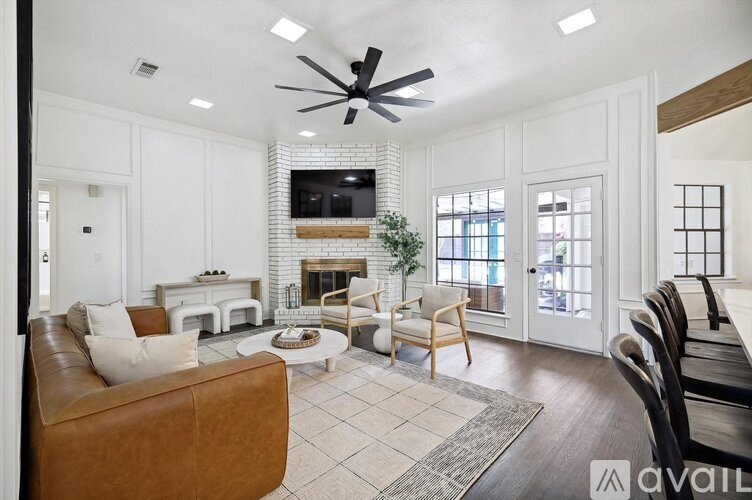 A living room with a brown leather couch and a white fireplace.