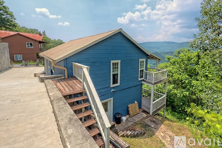 A blue house with a wooden deck and stairs leading to the front door.