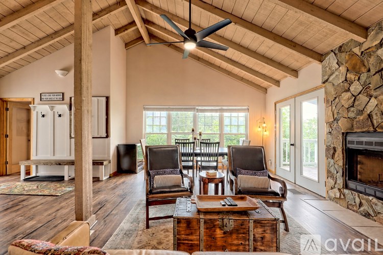 A living room with a stone fireplace and a ceiling fan.
