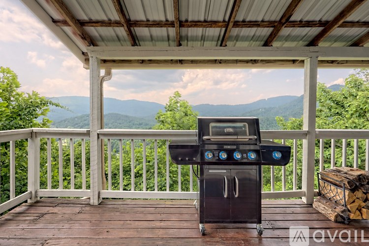 A BBQ grill is on a wooden deck with mountains in the background.
