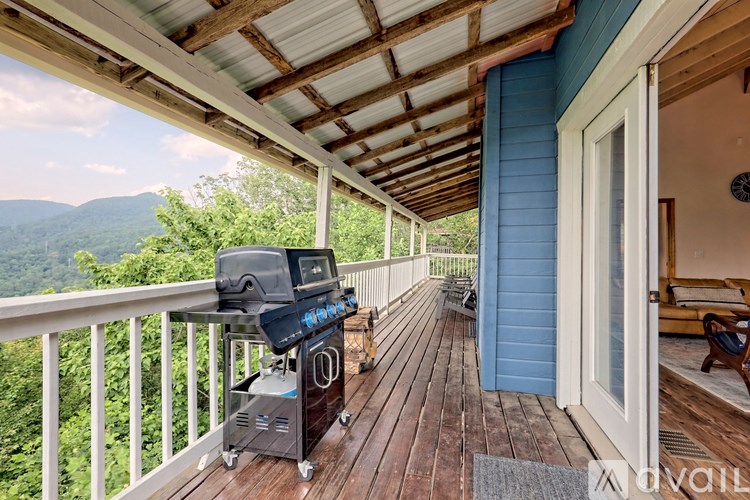A BBQ grill is on a wooden deck with a mountain view.