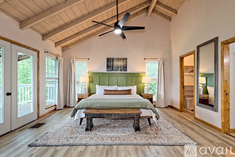 A bedroom with a bed, a bench, and a ceiling fan.