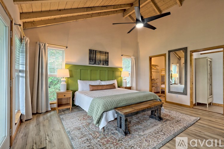 A bedroom with a bed, a bench, and a ceiling fan.