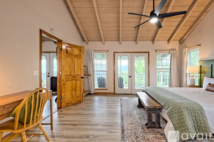 A bedroom with a bed, a chair, and a ceiling fan.
