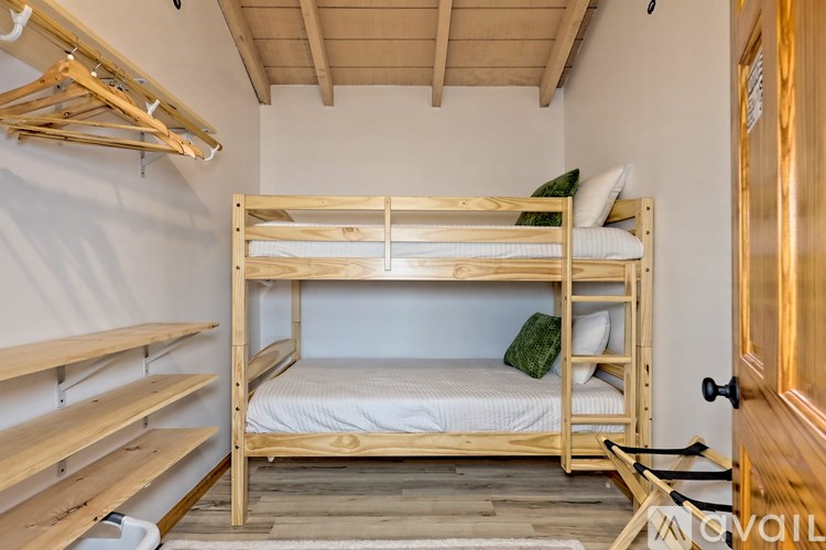 A wooden bunk bed with a ladder and a single bed with pillow and blanket.
