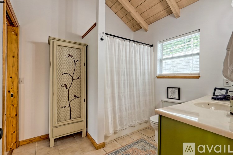 A bathroom with a white sink and a wooden cabinet with a tree design.