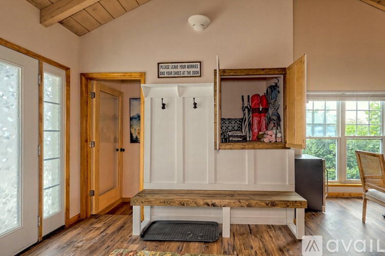A room with a wooden floor and a bench in front of a cabinet with a sign on the wall.