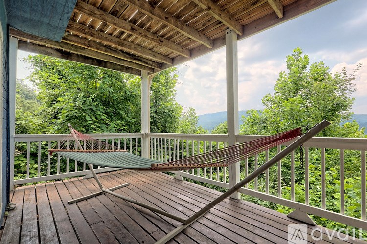 A wooden porch with a hammock and a view of the forest.