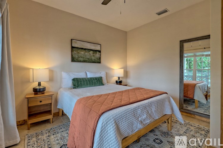 A bedroom with a large bed and two lamps on either side of the bed.