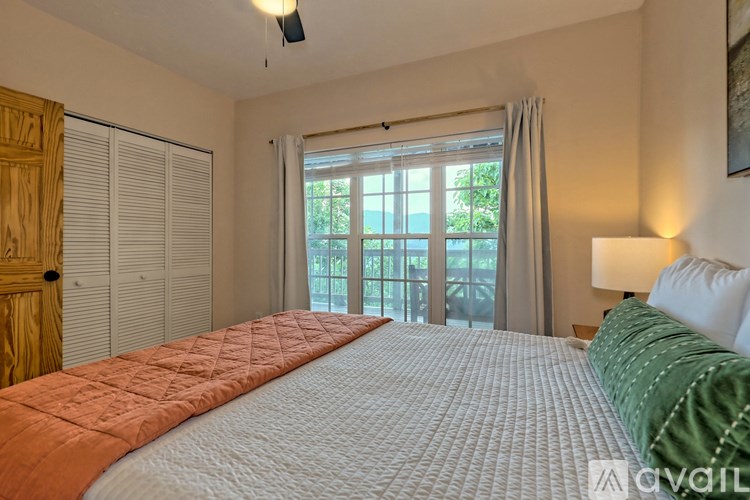 A bedroom with a large bed and a window with curtains.