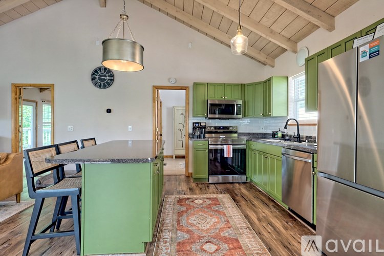 A kitchen with green cabinets and a stainless steel refrigerator.