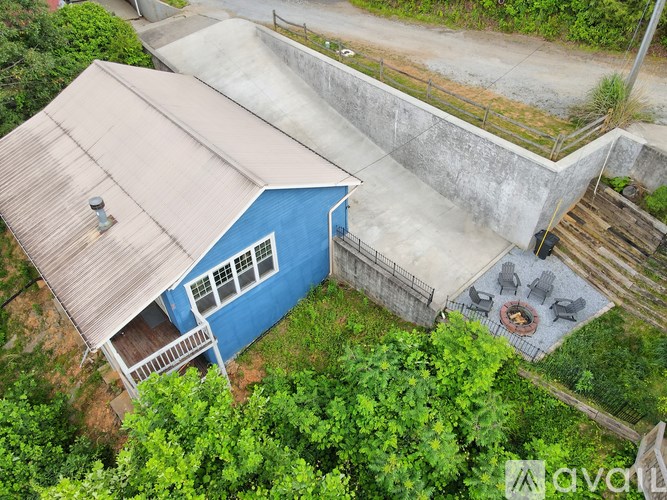 A blue house with a brown roof and a patio with a fire pit.