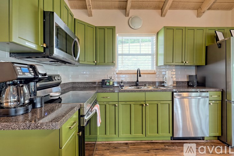 A kitchen with green cabinets and a stainless steel refrigerator.