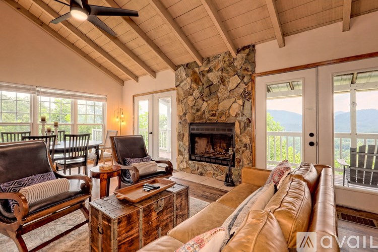 A living room with a stone fireplace and a large window.