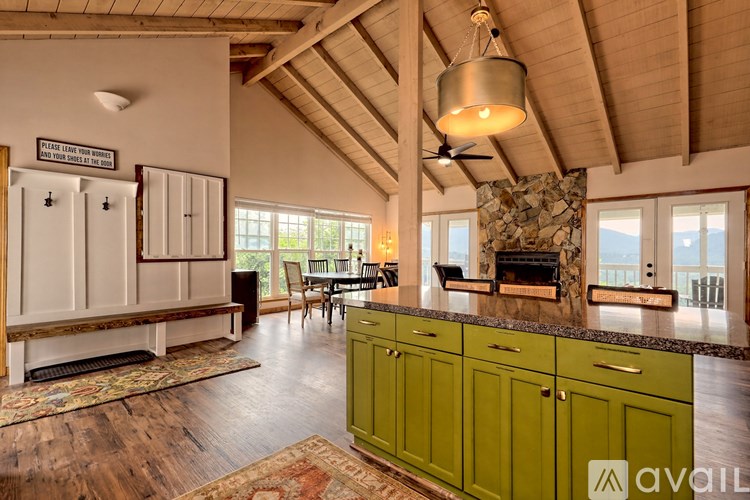 A living room with a stone fireplace and green cabinets.