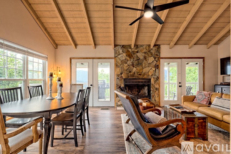 A living room with a stone fireplace and wooden furniture.