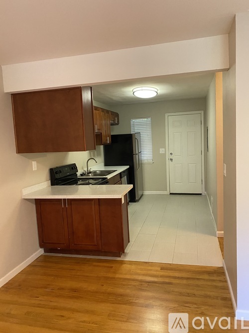 A kitchen with wooden cabinets and a black refrigerator.