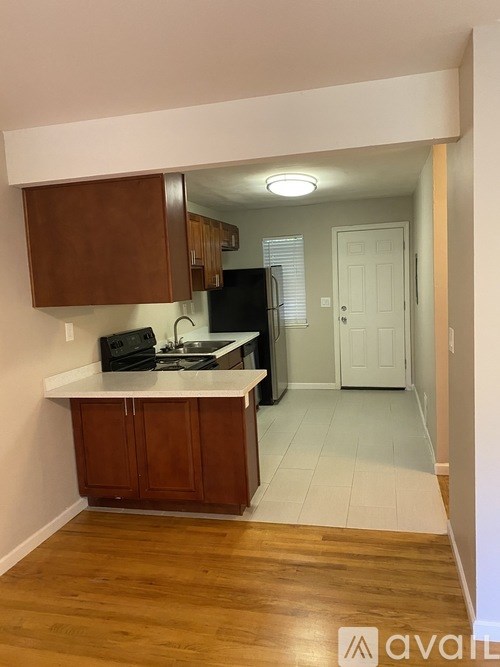 A kitchen with wooden cabinets and a black refrigerator.