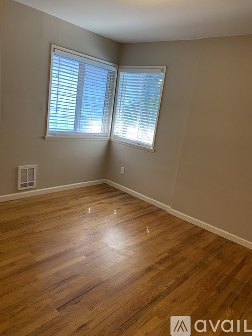 A room with wooden flooring and a window with blinds.