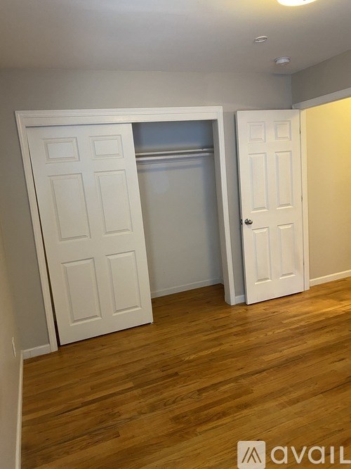 A room with a white door and a wooden floor.