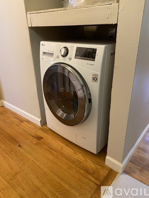 A white front loading washing machine in a room with wooden flooring.