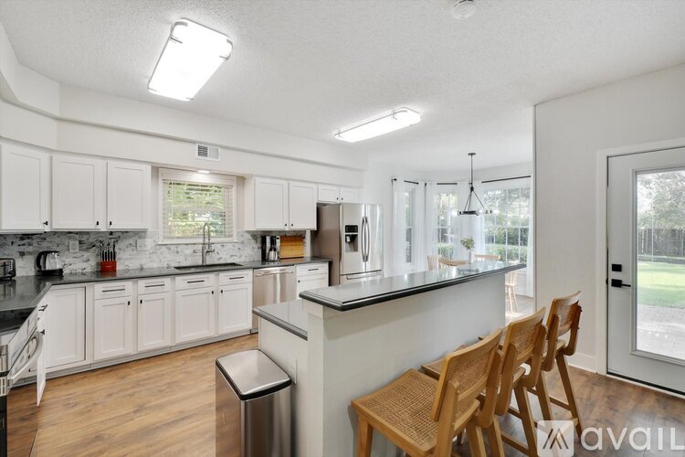 A kitchen with white cabinets and a black counter top.