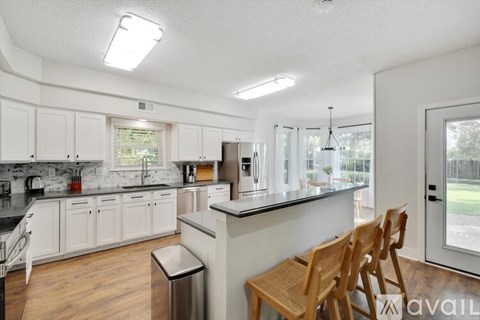 A kitchen with white cabinets and a black counter top.