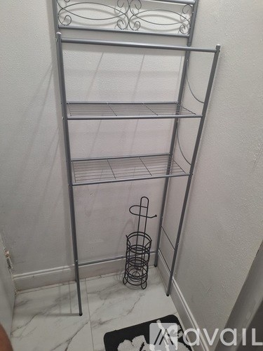 A metal rack with three shelves and a basket on the floor.