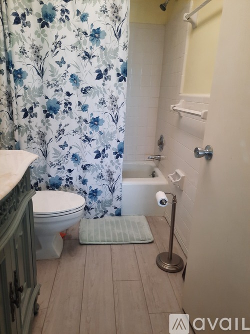 A bathroom with a floral shower curtain and a white toilet.