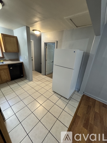A kitchen with a white fridge and a white tile floor.