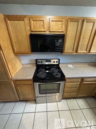 A kitchen with wooden cabinets and a black stove top oven.