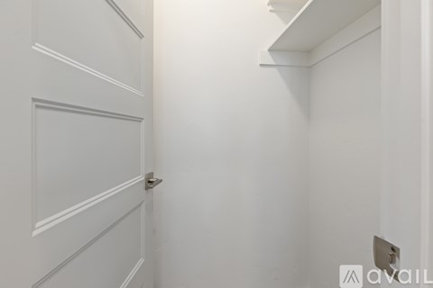 A white door with a silver handle is on the left and a white shelf is on the right.