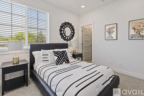 A bedroom with a black and white bed, a round mirror, and a wall-mounted shelf.