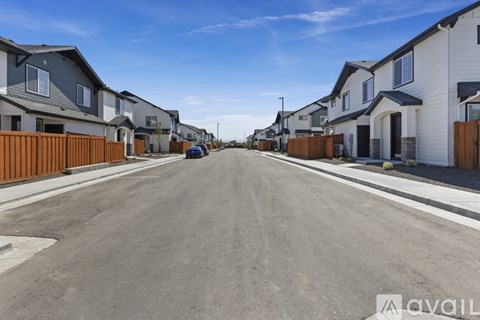 A street view of a residential area with houses on both sides and a car parked on the left.