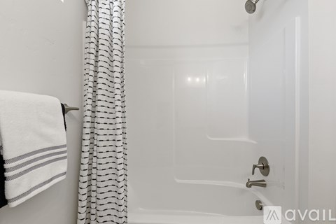 A white bathroom with a shower and a towel hanging on the wall.