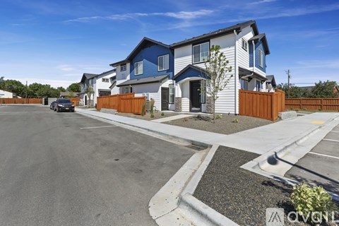 A modern two-story house with a blue and white exterior and a brown fence.