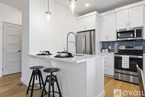 A kitchen with white cabinets and a white island with a sink.