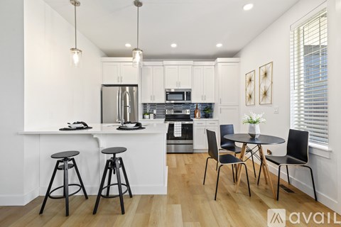 A kitchen with white cabinets and a wooden floor.