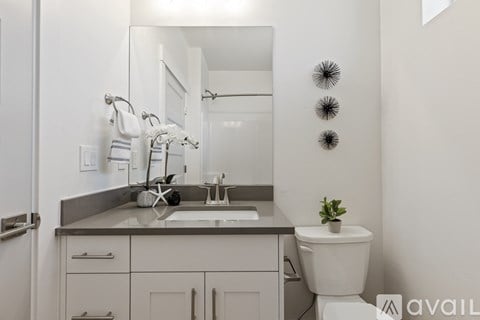 A bathroom with a toilet, sink, and mirror.